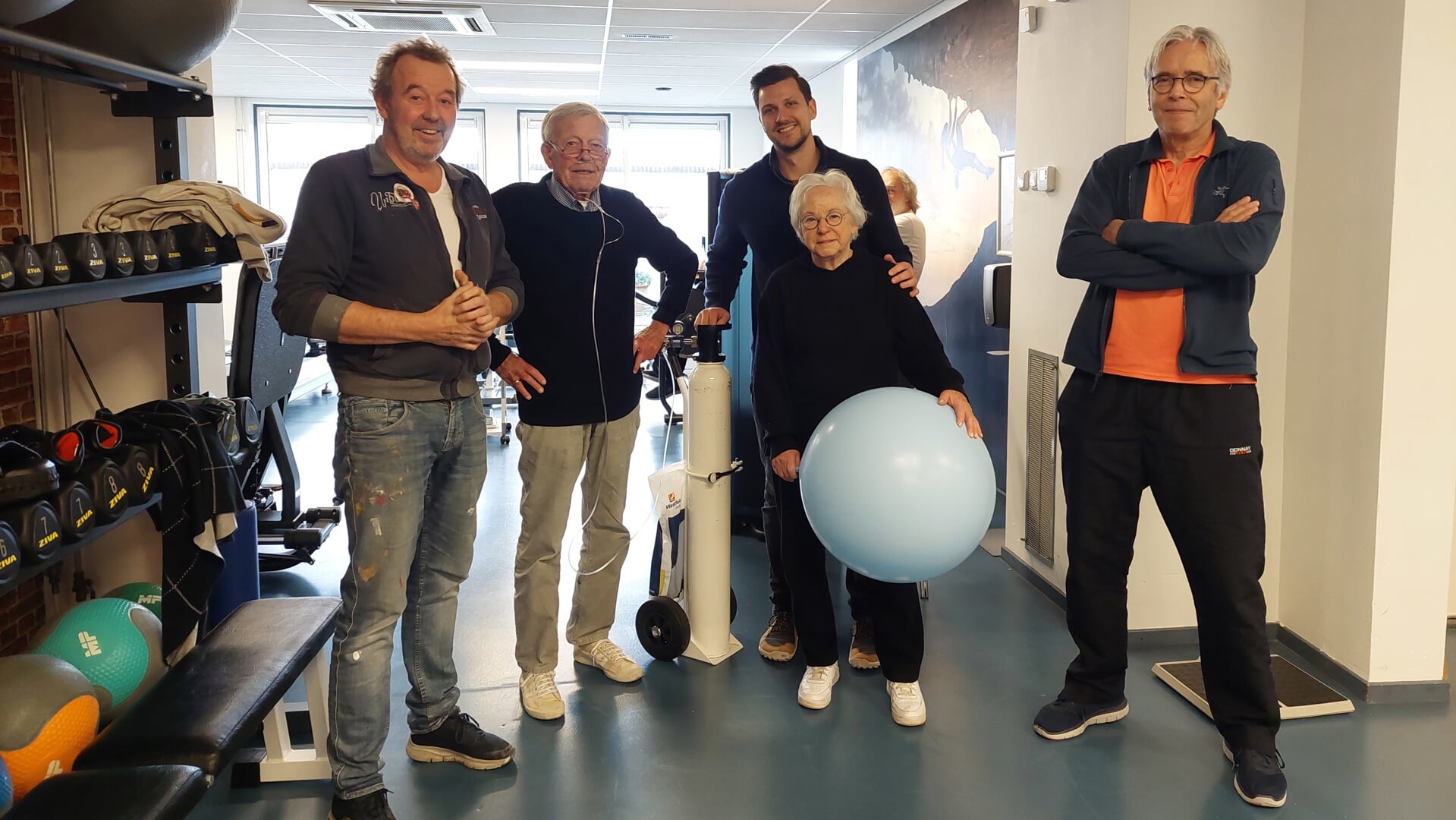 Fysiotherapeuten René Zegers, Sander Roverts en Ronald Kok met tussen hen in twee cliënten die ook blij zijn dat de praktijk weer is opgeknapt.