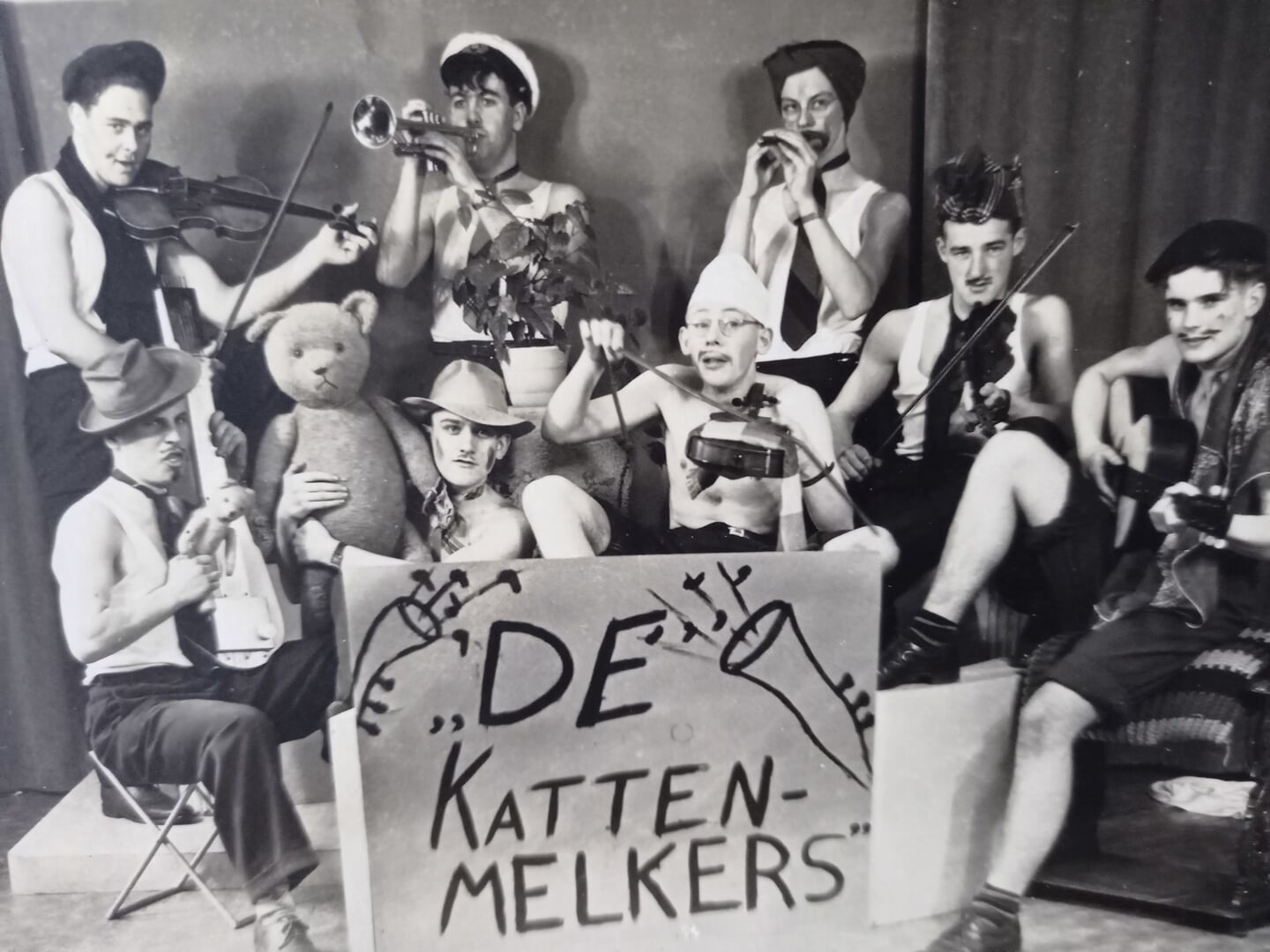 Vrienden uit het centrum in een jolige pose als de muziekgroep 'De kattenmelkers'. Jan Bakker 'bespeelt' rechtsboven de trompet. Op de foto onder meer Hein van Schuppen, Gert Dijkstra (van de bakker), Wim Radding, Van Ojik en Weijers (wit petje) uit Scherpenzeel. Omstreeks 1945.