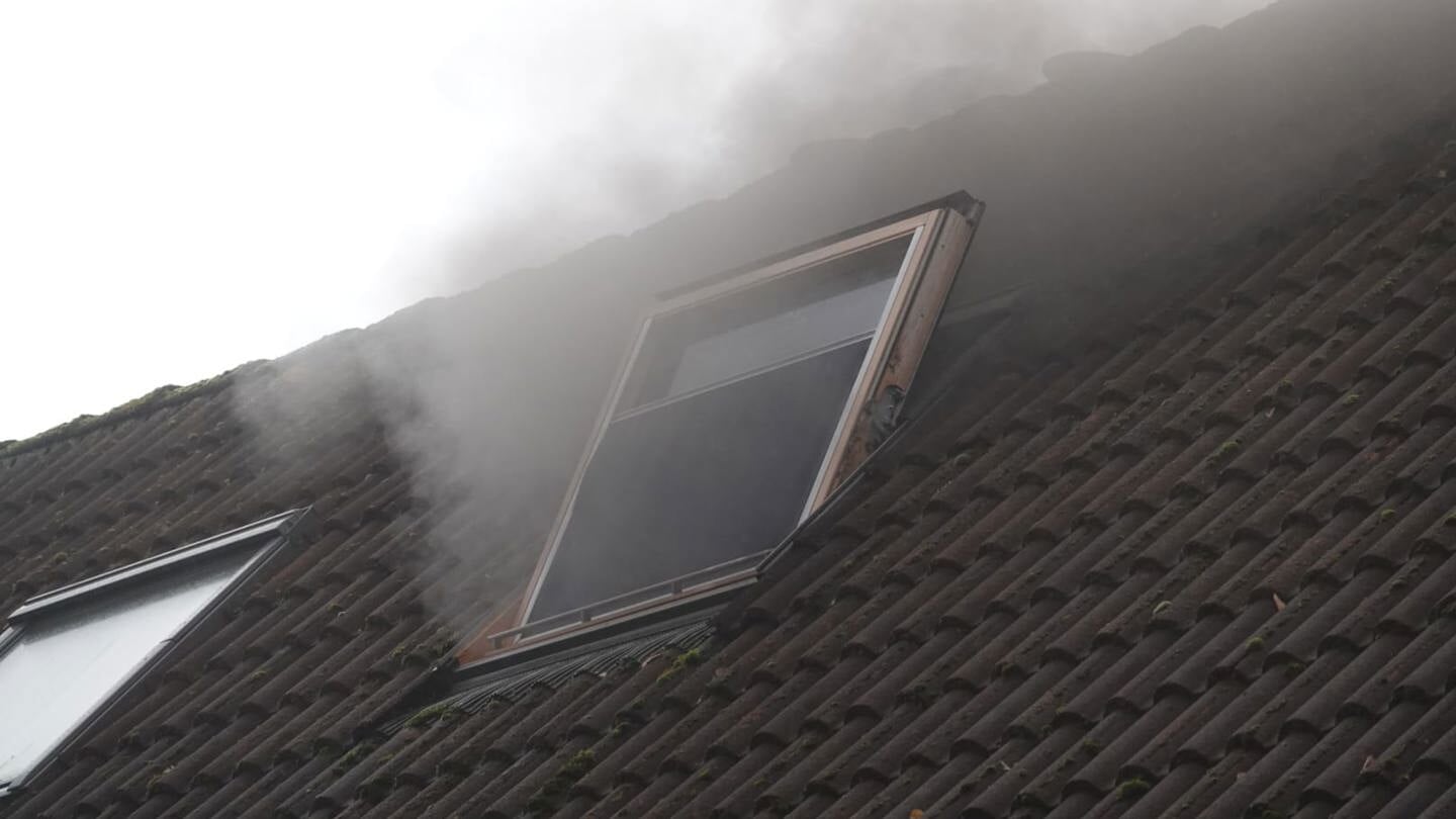 Donkere rook komt uit het zolderraam van een woning aan de Van Schothorststraat in Barneveld.
