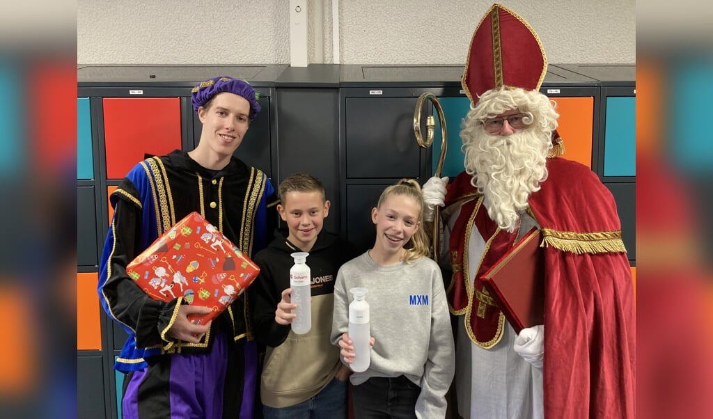 Leerlingen Tieme en Jasmijn ontvangen uit handen van Sinterklaas een mooie, duurzame dopper. Op de dopper staat het logo van Schans en de naam van de leerling.