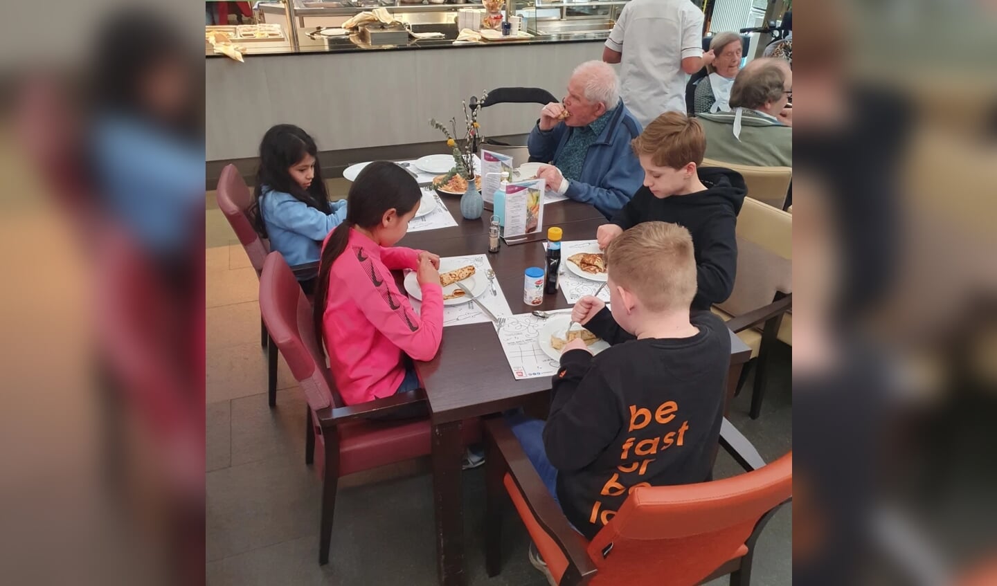 Leerlingen en bewoners eten samen pannenkoeken