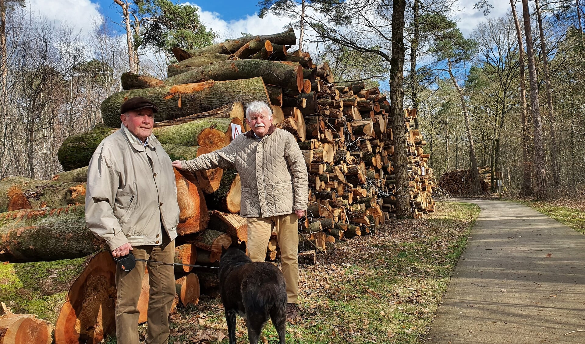 Ben de Haas (rechts) en zijn buurman bij de immense stapels omgezaagde bomen. ,,Wij worden hier heel verdrietig van", klinkt het in koor.