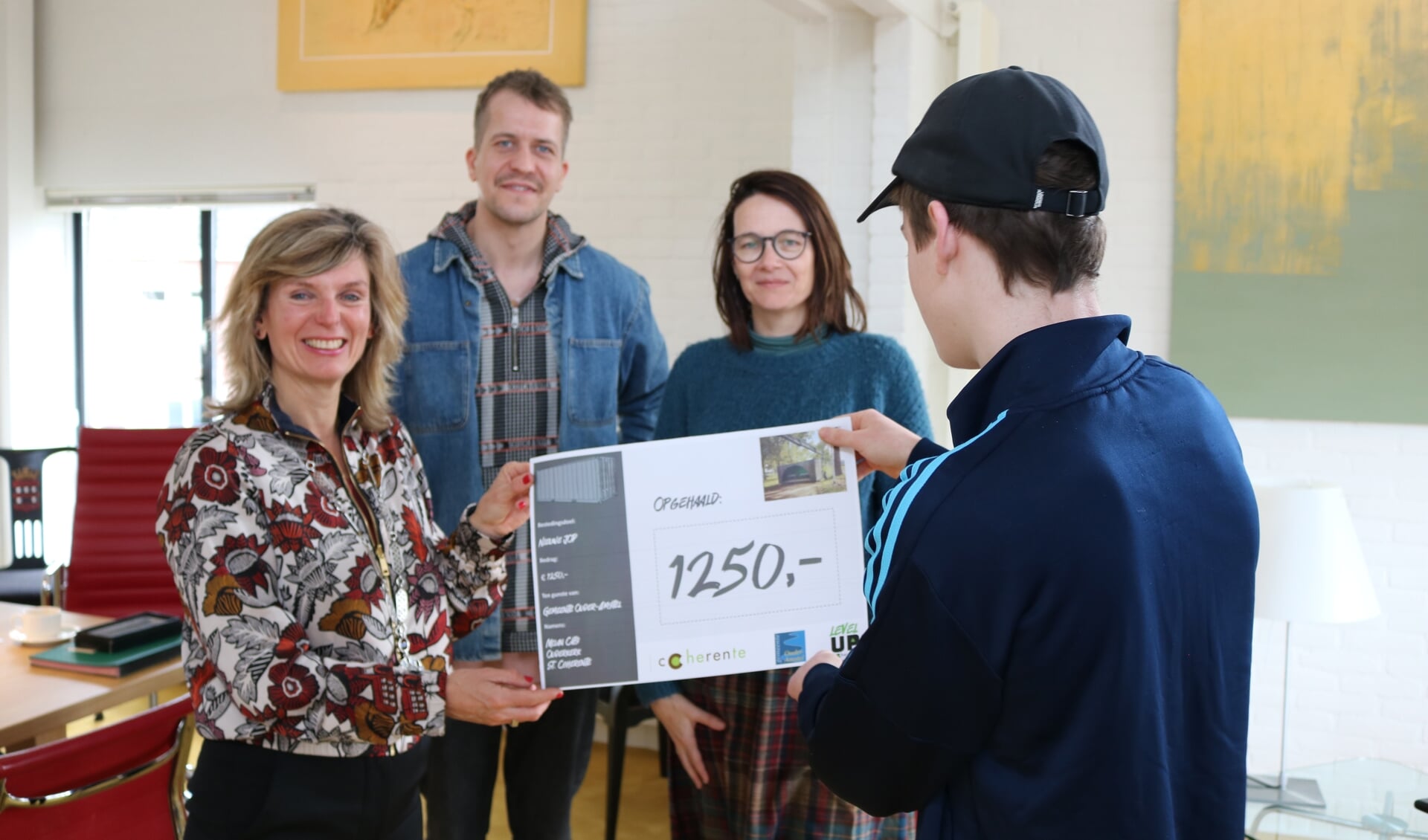 Burgemeester Joyce Langenacker ontvangt een cheque van Milan Cats voor de nieuwe JOP. Ook op defoto jongerenwerker Robbert-Jan en moeder van Milan, Nathalie Cats.