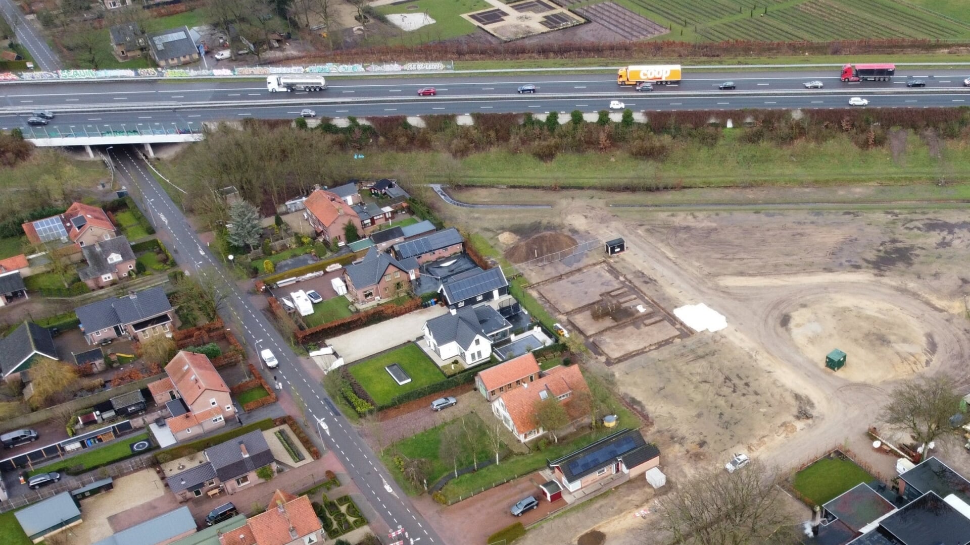 De Tolnegenweg in Stroe met bovenaan de A1. Links van de parallel aan de weg staande twee-onder-een-kapwoning met het oranje dak (aan de linkerkant van de foto) wordt een nieuwe vrijstaande woning gebouwd.