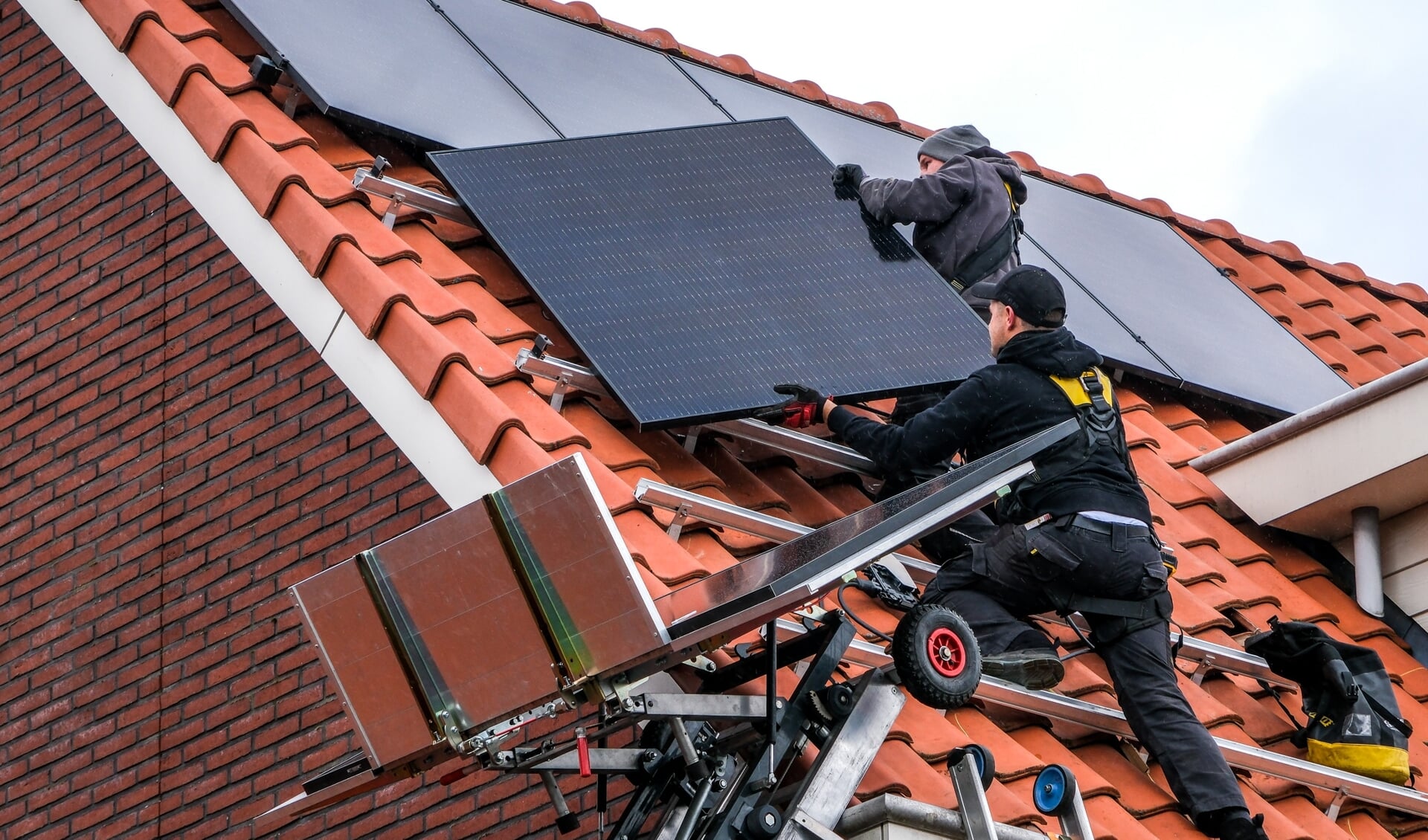 De twee monteurs van Energie Studio plaatsen zonnepanelen op het dak.