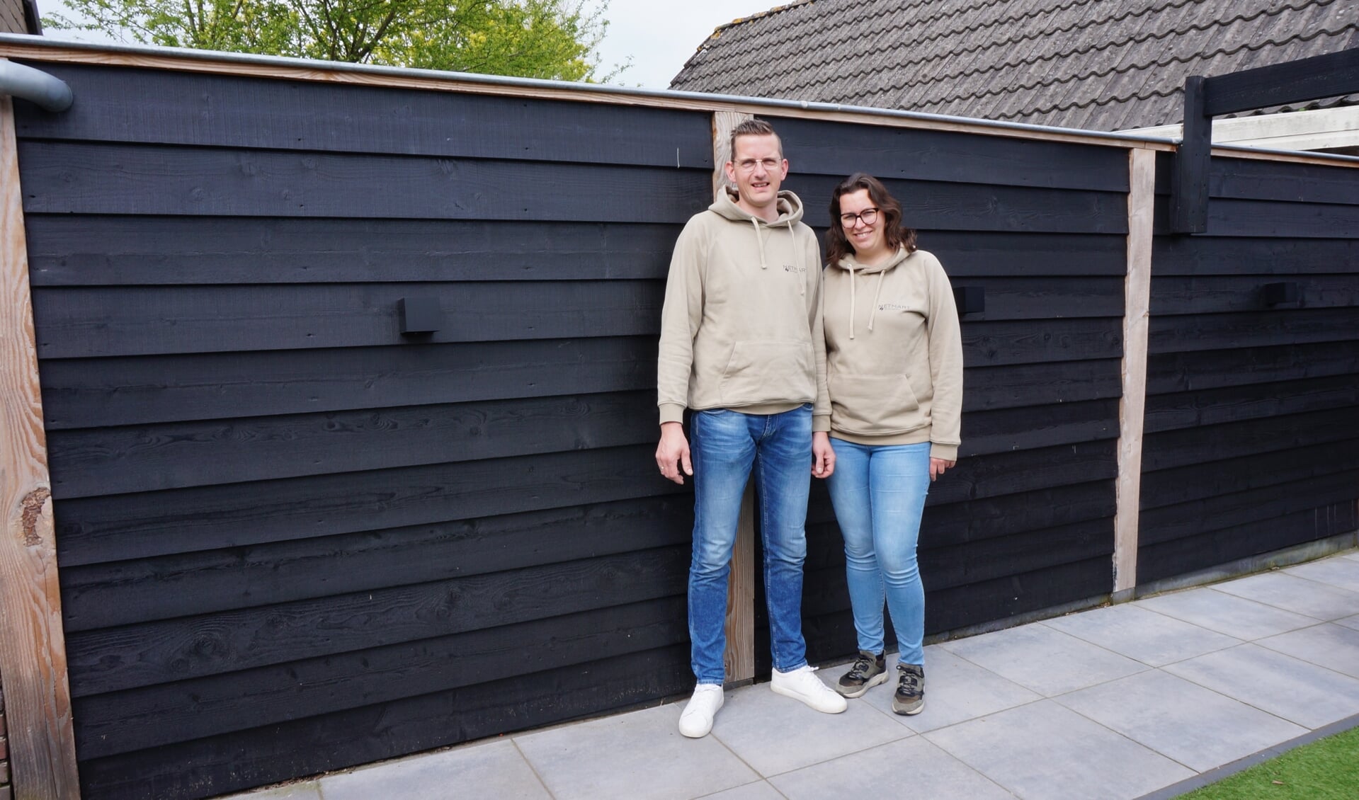 Martin en Miranda Vos bij hun zelfgebouwde houten schutting in hun eigen tuin.