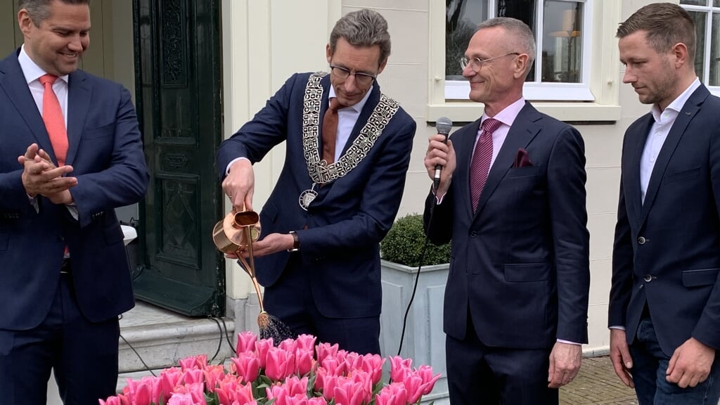 Burgemeester Poppens doopt de Wester-Amstel tulp met bijpassende roze champagne. Links van hem naamgever Thomas Wals en rechts ceremoniemeester Søren Ludvig Movig en kweker Jan-Willem Ligthart.