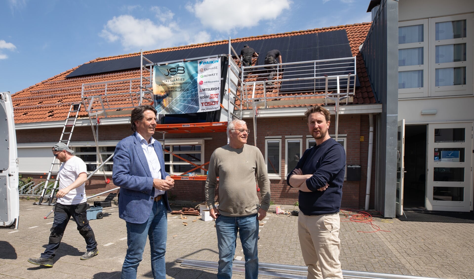 De wethouders Hugo Prakke (links) en Steven de Vries met speeltuinvoorzitter Ton Gesgarz (midden) bij de plaatsing van de zonnepanelen vrijdag. 
