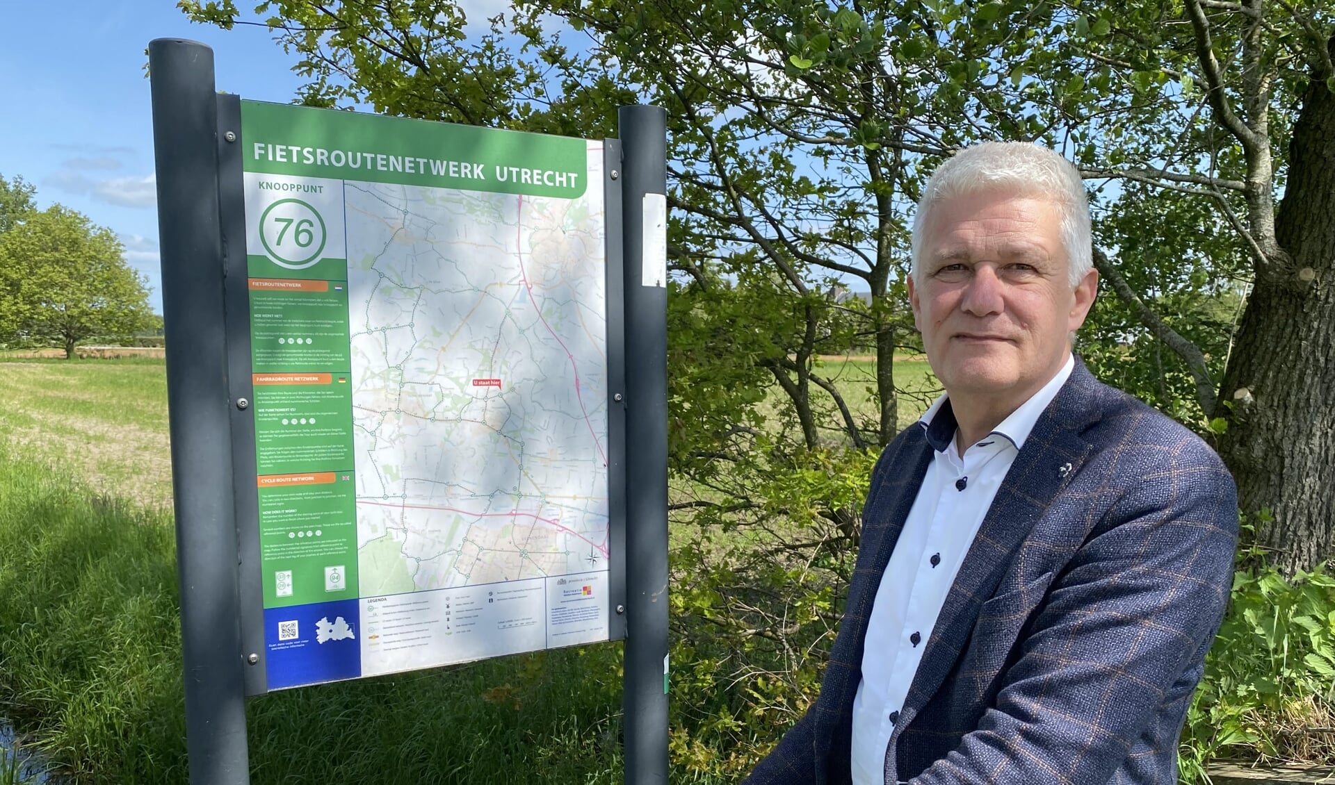 Wethouder Henk van der Schoor bij een bord van het Fietsroutenetwerk Utrecht bij het dijkje naar Fort Daatselaar.