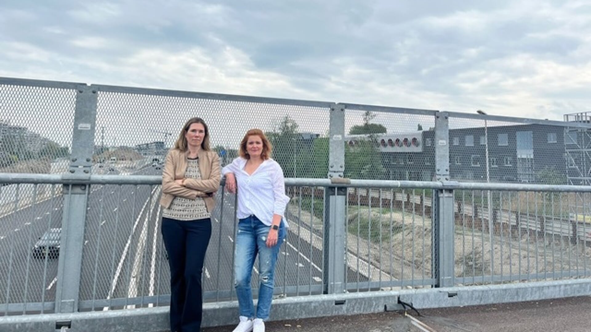 De VVD-raadsleden Femke Lagerveld en Elisa De Marco (rechts) op de tijdelijke brug boven de A9. Aan weerskanten van de snelweg staan schoolgebouwen. De twee hadden via vragen aan het college aandacht gevaagd voor de luchtkwaliteit.