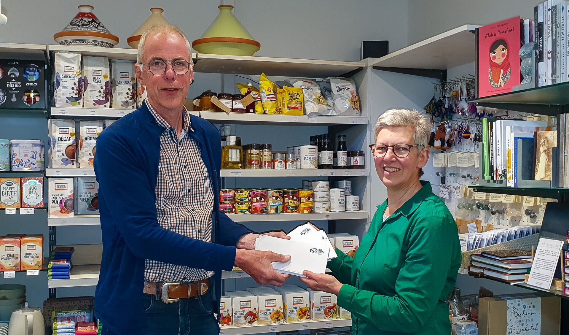 Voorzitter Ginny Mulder van de Wereldwinkel overhandigt de bonnen aan secretaris Klaasjan Andringa van de Voedselbank.