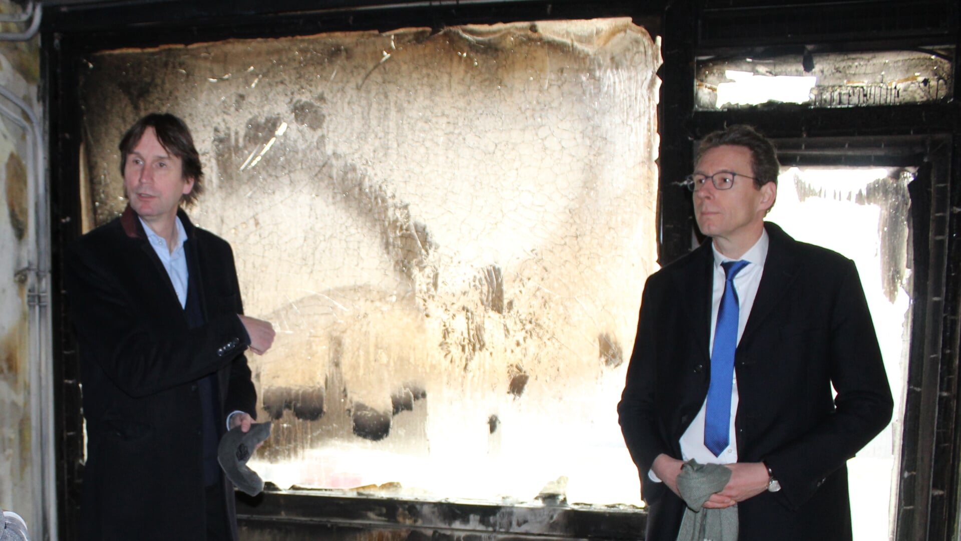 Wethouder Herbert Raat en burgemeester Tjapko Poppens tijdens een bezoek aan een uitgebrande etagewoning.
