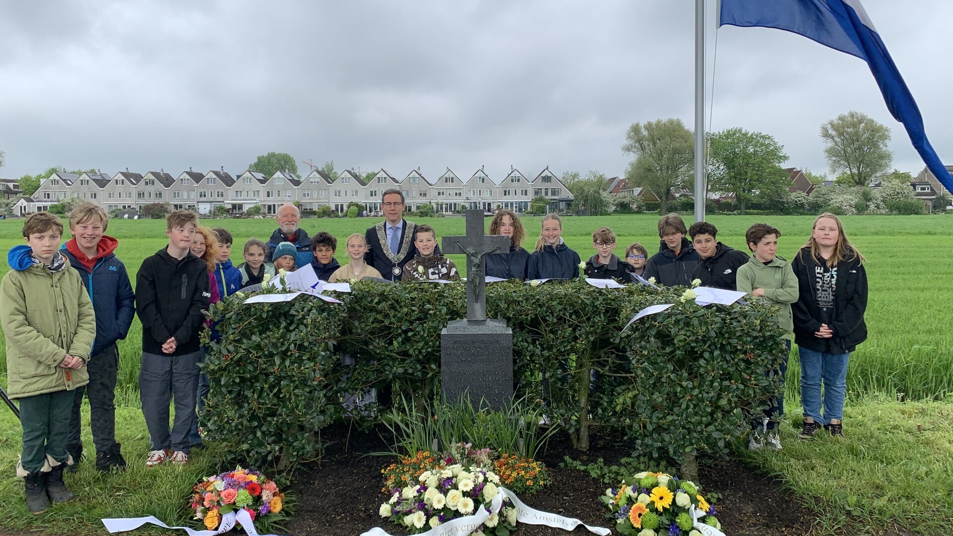Burgemeester Tjapko Poppens met leerlingen van basisschool De zwaluw bij het monument aan de Nesseraan.