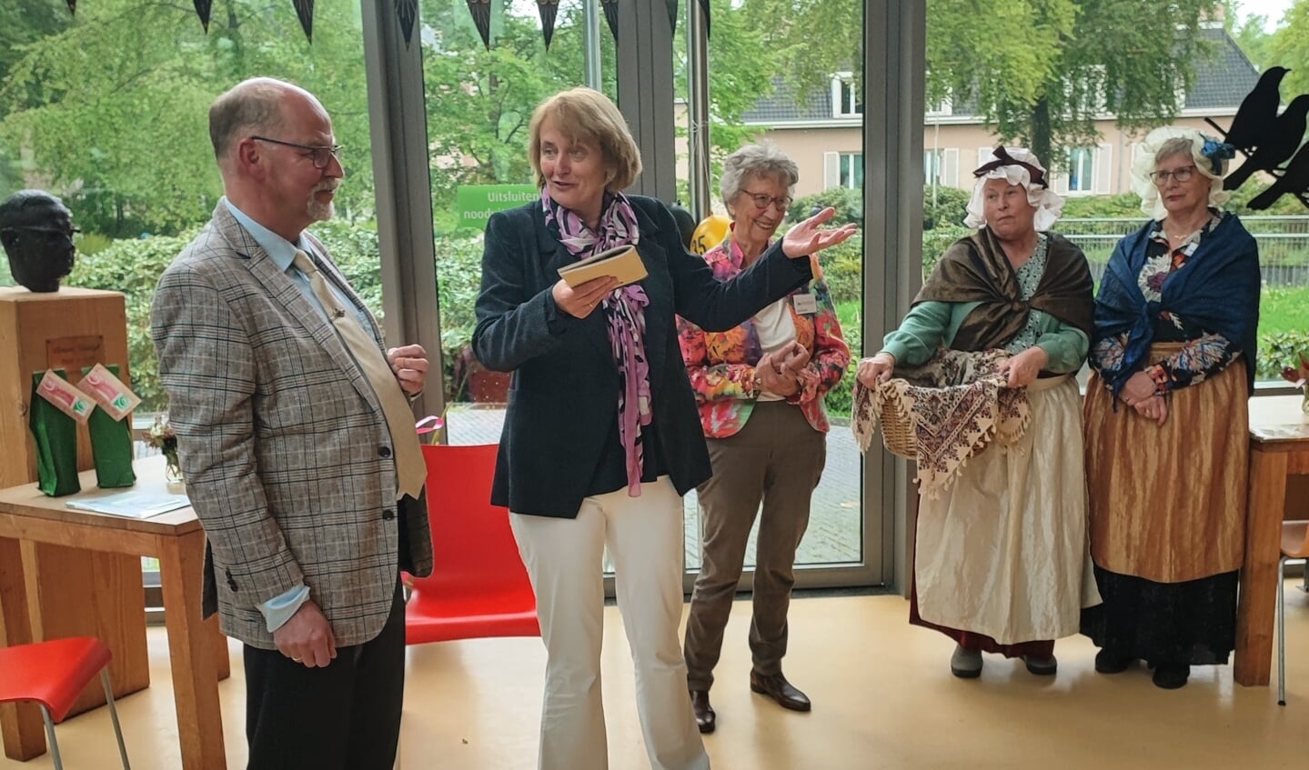  Erelid Roland van Barneveld overhandigde het jubileumboek aan wethouder Karin Oyevaar, onder toeziend oog van voorzitter Anneke Zevenbergen en Ien en Dien.