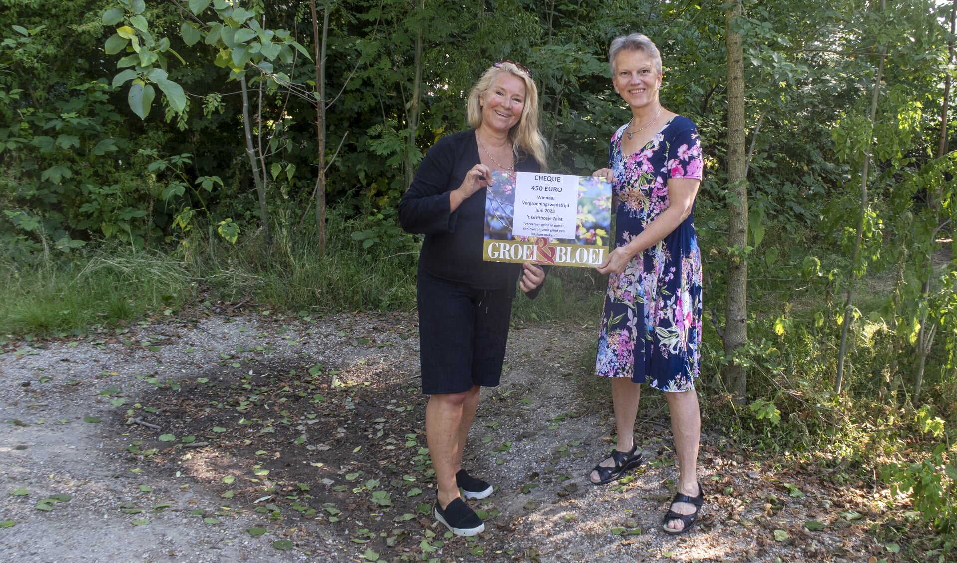 De voucher wordt uitgereikt door Ilse Kuiper (links secretaris Groei&Bloei) aan Ellen Teunissen (rechts vrijwilligster Griftbosje)