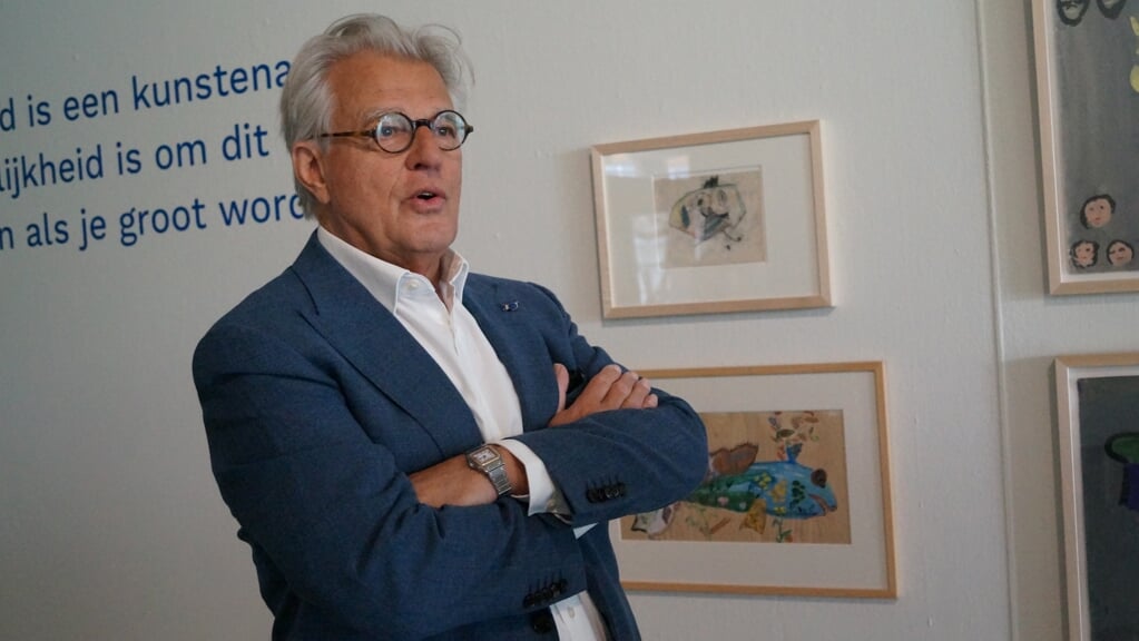 Jeroen Krabbé bij de twee kindertekeningen die hij voor de expositie 'Alle kinderen kunstenaar' beschikbaar heeft gesteld.