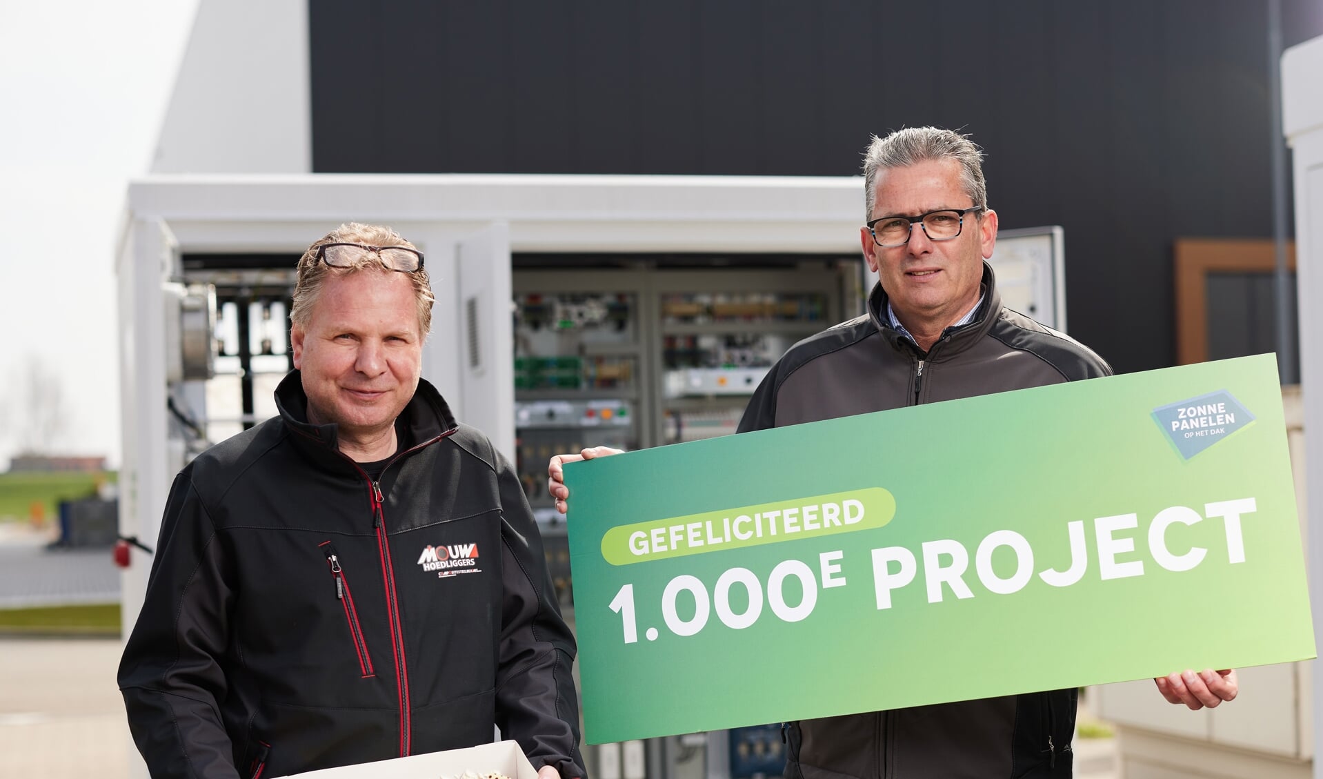 Edwin Mouw uit Ede (links) is eigenaar van de duizendste installatie van Zonnepanelen op het dak. Rechts Martin Valentijn.