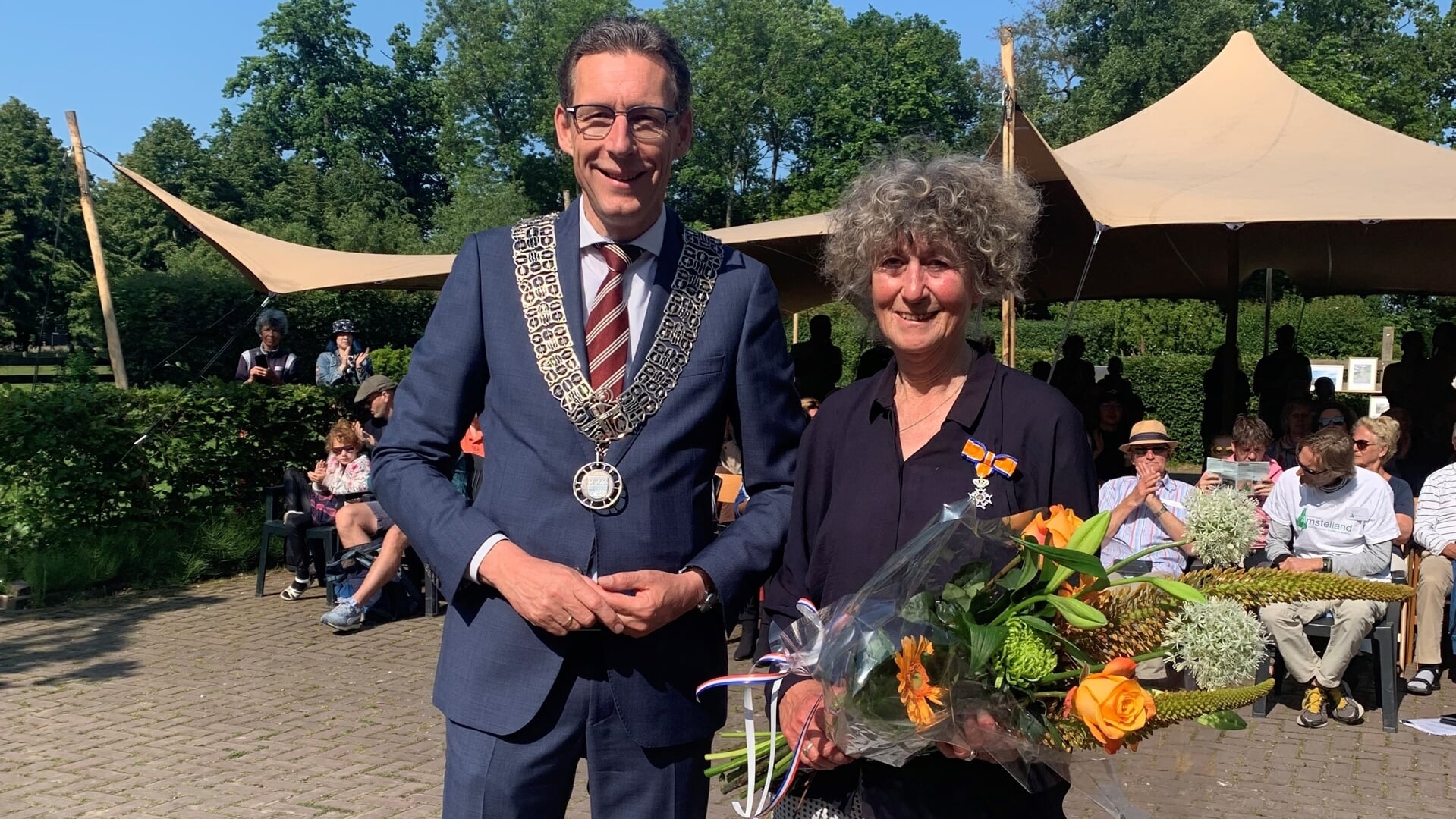 Renske Peters met de koninklijke onderscheiding die ze uit handen van burgemeester Tjapko Poppens heeft ontvangen.