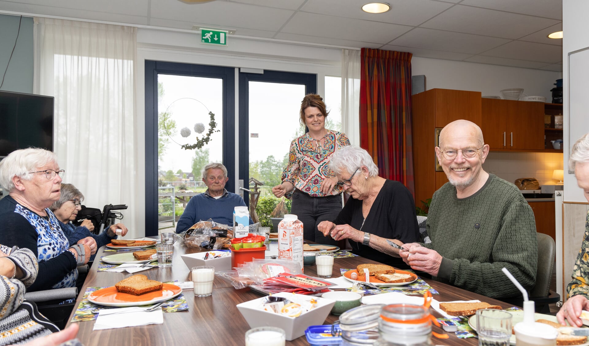 Dirk van Duijn in de groene trui, omringd door de andere deelnemers aan de dagbegeleiding. Tussen hen in staat medewerker bij de dagbegeleiding Petra Rodijk.