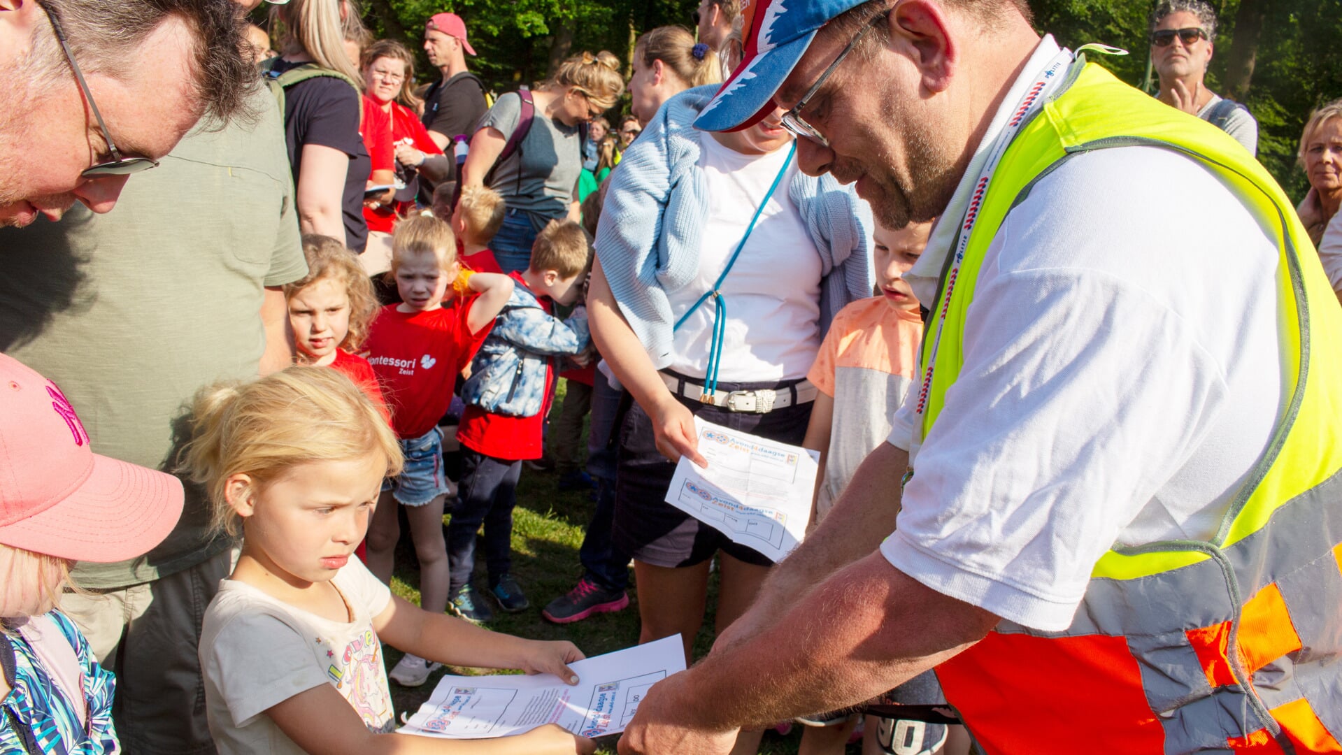 Voorzitter Ben Werner 'knipt' de deelnemerskaart van Nora van de Stroet. Deze vijfjarige wandelaar is de eerste deelnemer van de eerste mini4daagse van Zeist.