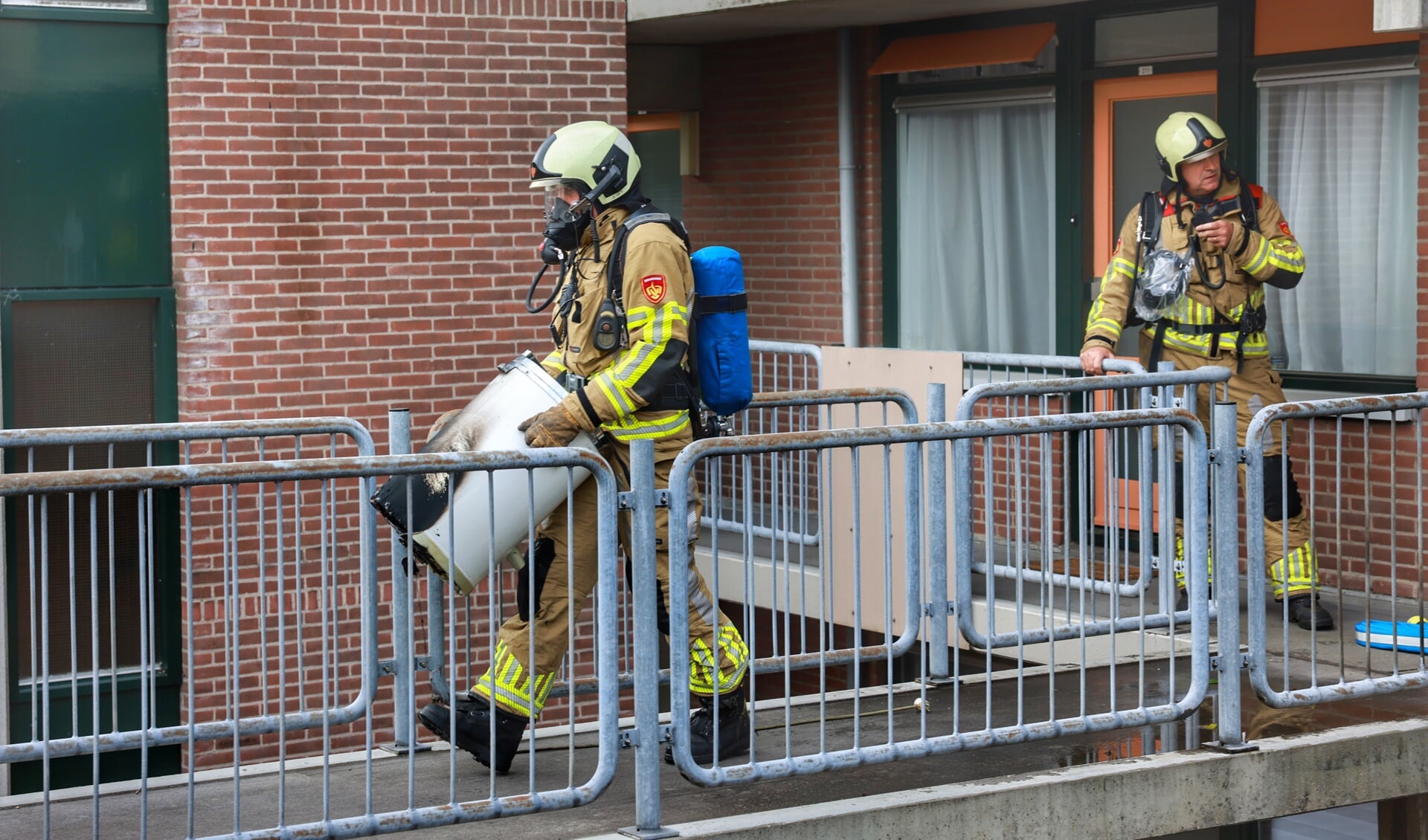 Een brandweerman draagt de boosdoener naar buiten. Blussen hoefde niet meer maar de woning stond wel vol rook.