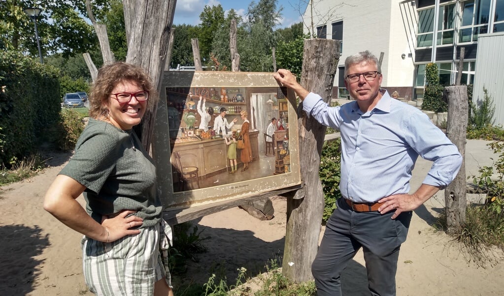 Astrid Miltenburg en René van Duist voor een plaat van een historische kruidenierswinkel, bij de Delteykschool