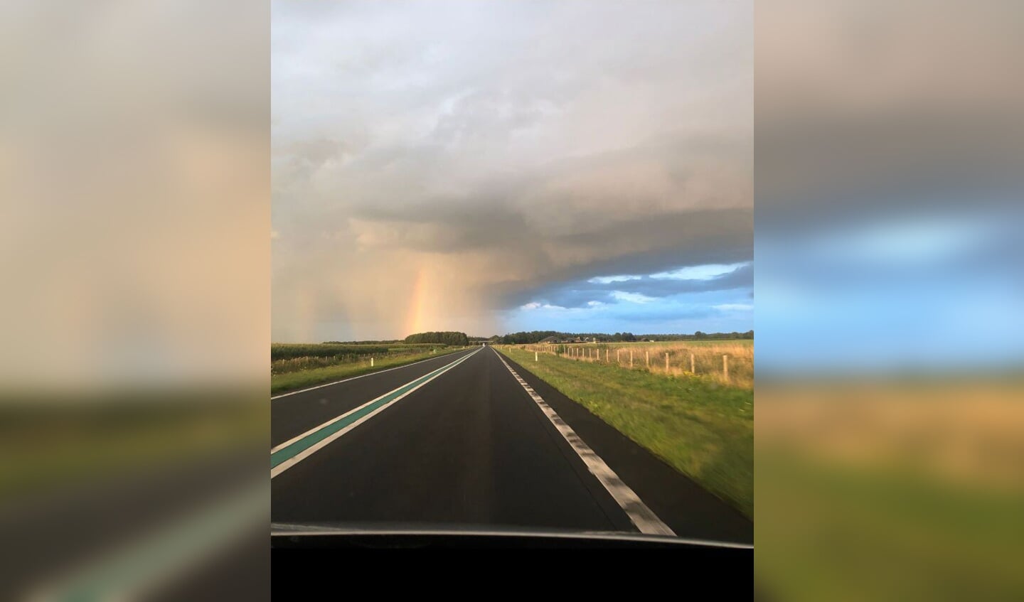 Regenboog die tevoorschijn komt uit een regenboog, op de weg tussen Ommen en Hardenberg.