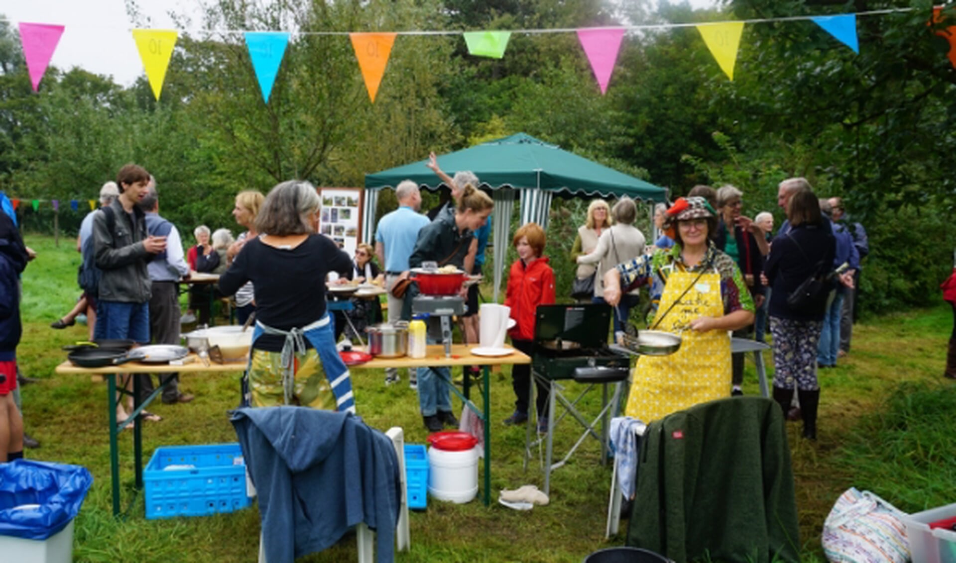 Bezoekers en vrijwilligers genieten van het jubileum en van de pannenkoeken.