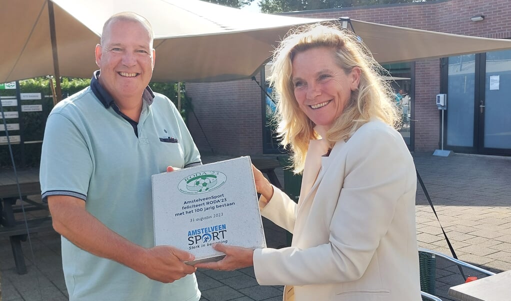 Directeur Heleen van Ketwich Verschuur van AmstelveenSport overhandigt de jubileumtegel aan RODA‘23-voorzitter Ronald Posthumus.