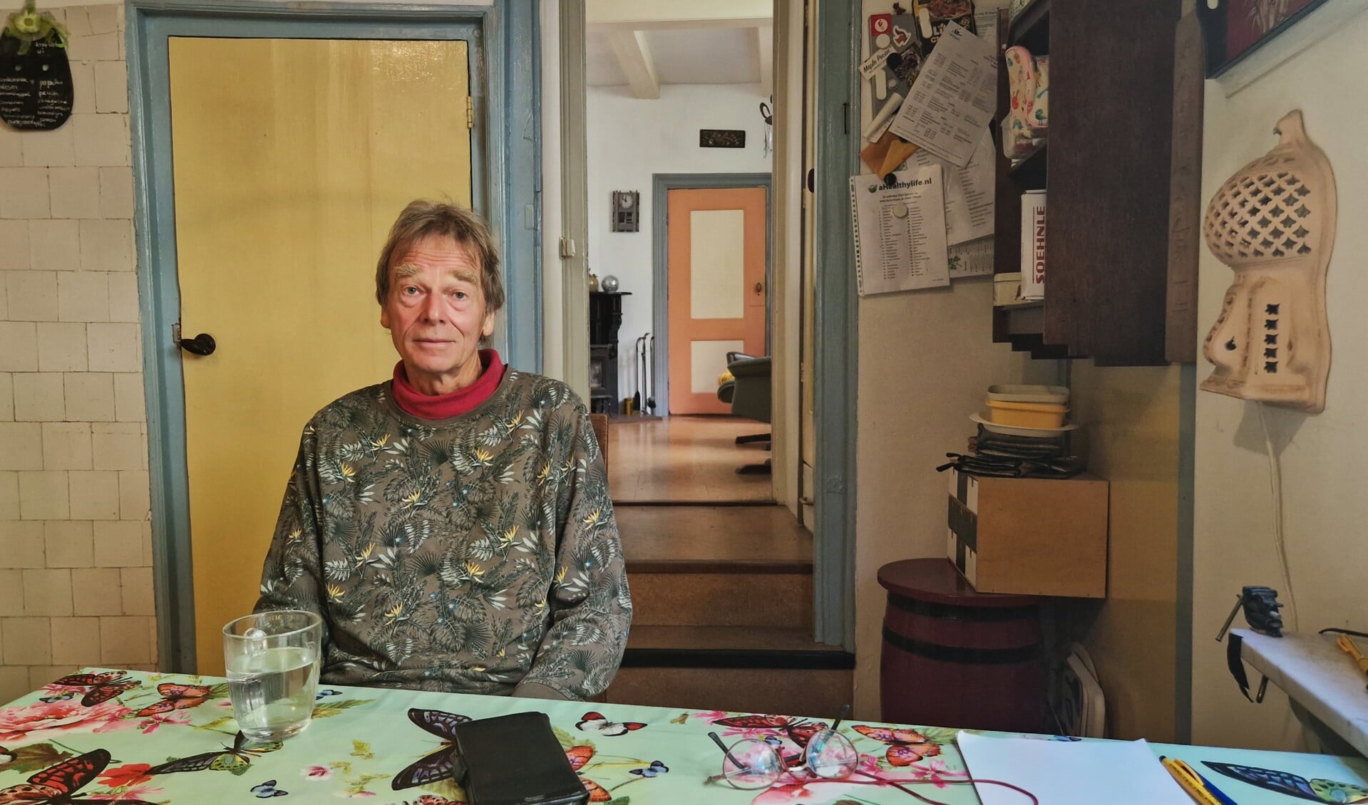 Bert aan zijn keukentafel met op de achtergrond de opkamer.