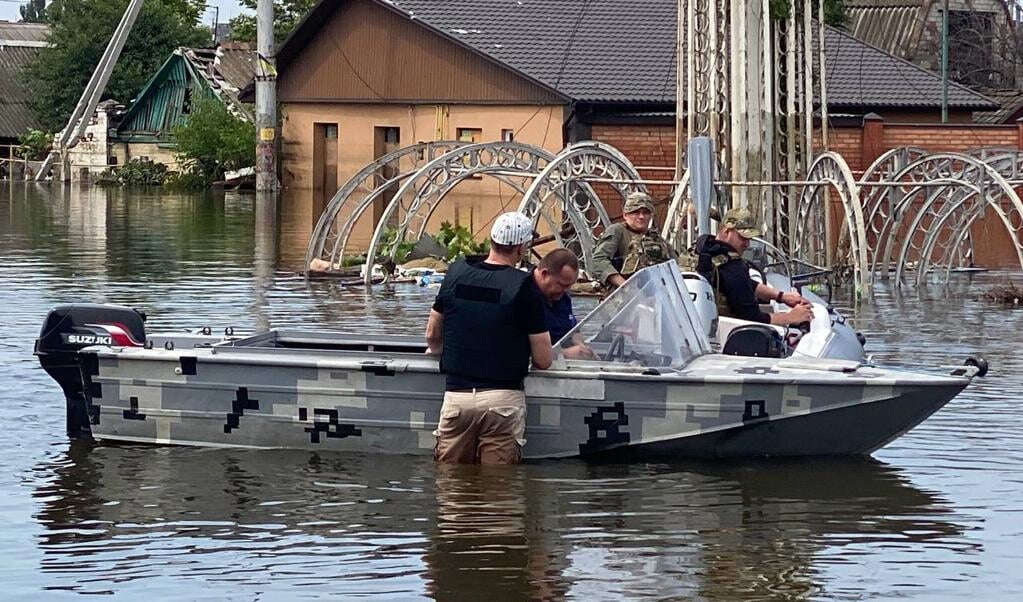 Hulpverleners met de motorboot na de doorbraak van de dam bij Cherson.
