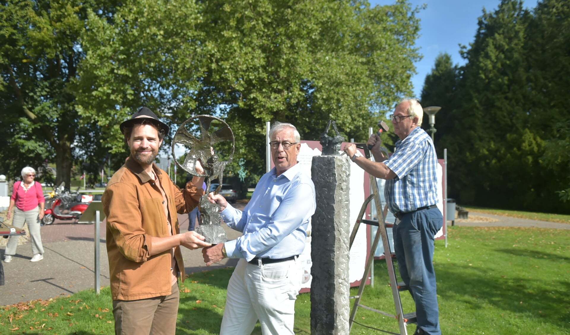 Tibo van de Zand (links) en Paul Tirion met het brozenbeeld De Parachutist. Medewerker Cor verwijdert het restant van het gestolen kunstwerk.