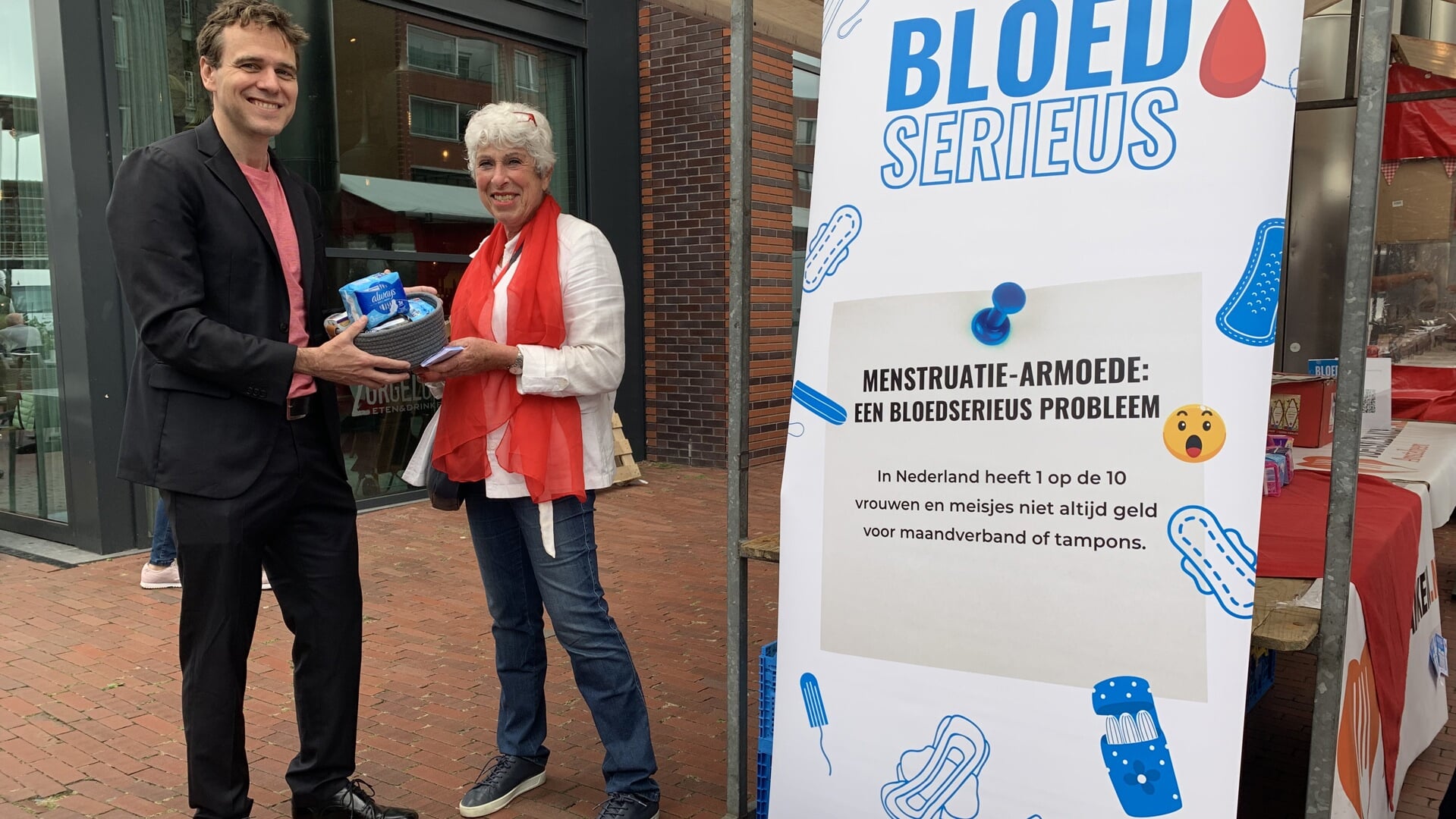 Wethouder Marijn van Ballegooijen overhandigt een pakket bij de inzamelingsactie van de Voedselbank.