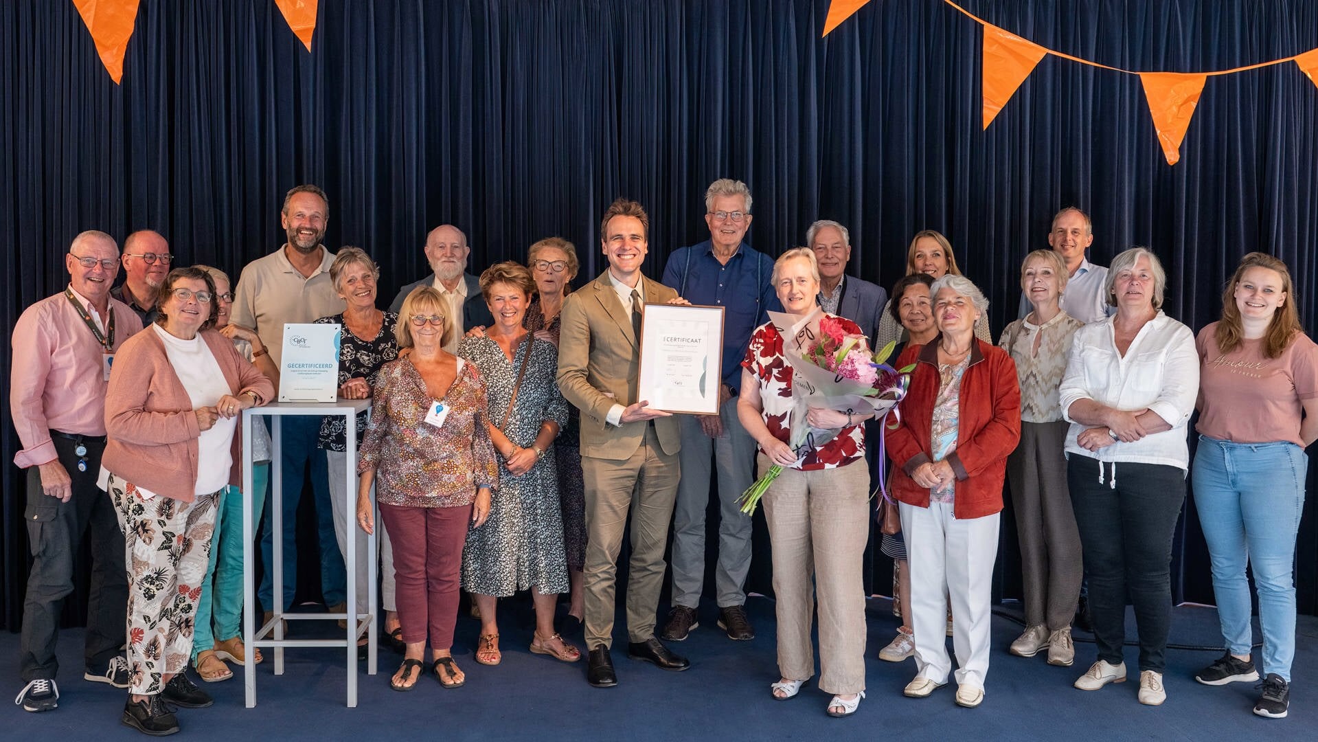 Wethouder Marijn van Ballegooijen toont het behaalde certificaat met Dirma Nagelhout (Coördinator Taalhuis Amstelland) en vrijwilligers van het Taalhuis.