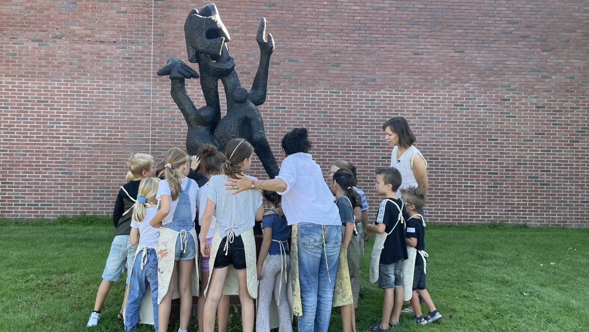 De deelnemende kinderen lieten zich inspireren door kunstwerken van Cobra-kunstenaars. Hier staan ze bij het beeld 'De Gek' van Lotti van der Gaag dat buiten naast het Cobra Museum staat.