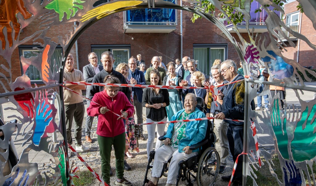 Bewoners en leerlingen knippen het lint met belletjes door.