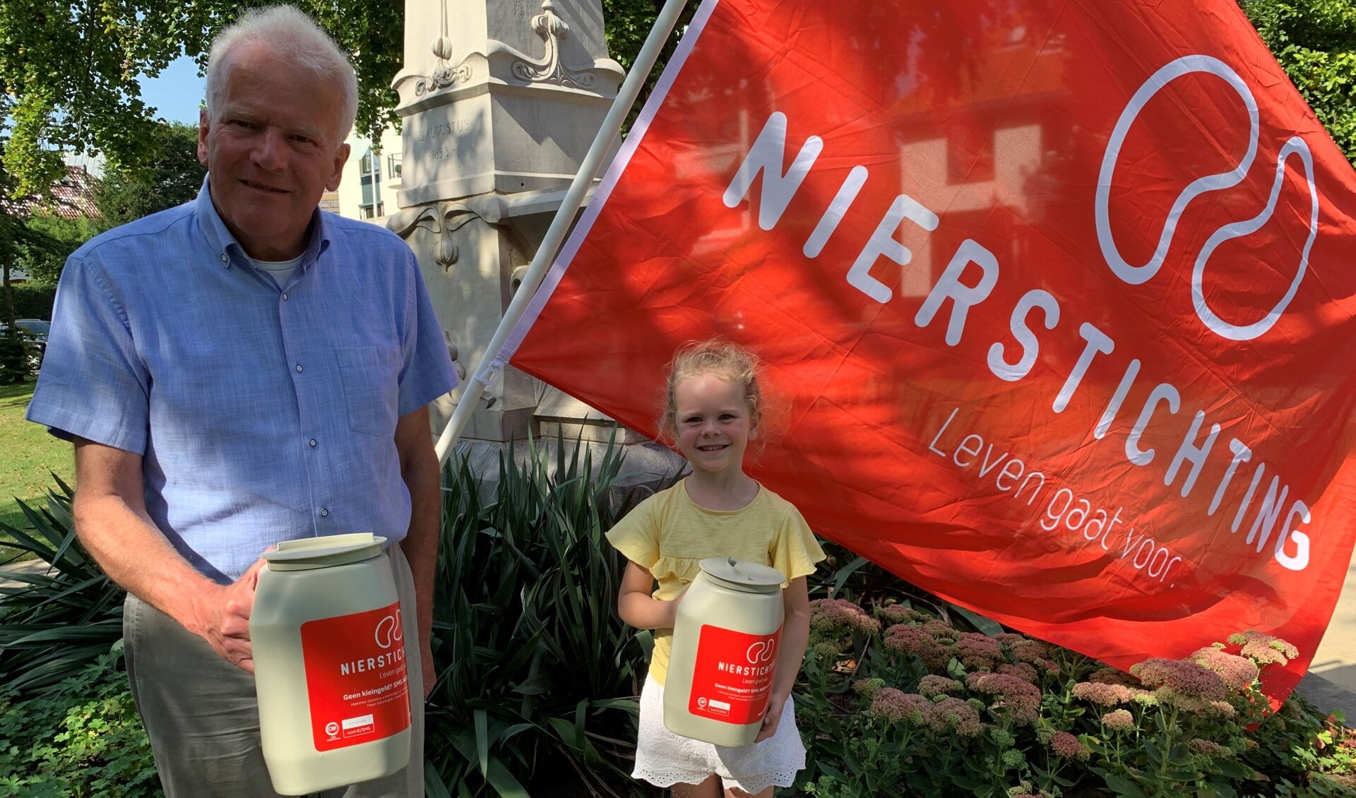 Tijdens decollecteweek hijst coördinator Piet M. Oskam met hulp van kleindochter Zarah de vlag van de Nierstichting in het Zeister Wilhelminapark om deze actie meerbekendheid te geven.