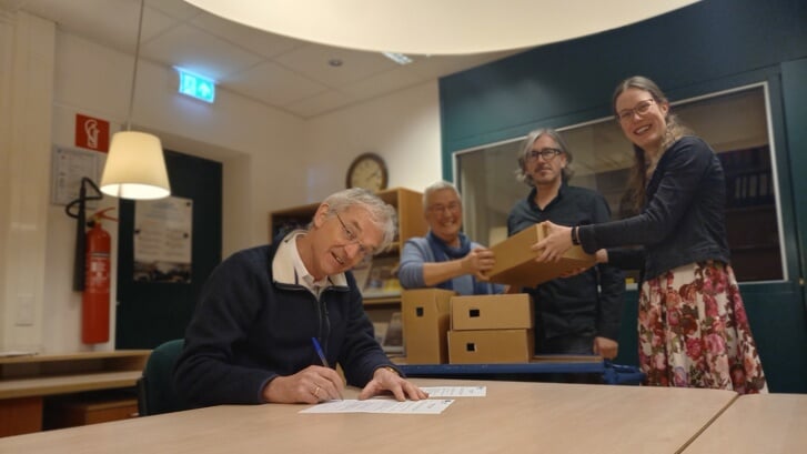Jan Rienk Bloembergen tekent het contract met de gemeente, Arina van Hulst (WAC), gemeentearchivaris Rob Urban en archiefspecialist Marinka Joosten kijken toe.