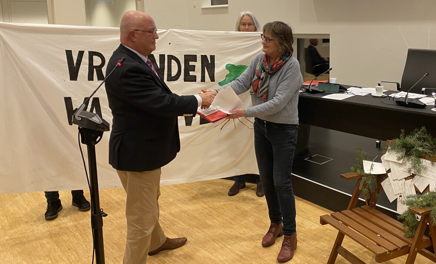 Actievoerster Van den Boer biedt de petitie aan aan de voorzitter van de vergadering: VVD-raadslid Aat Grinwis. 