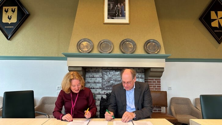 Wethouder Moniek van de Graaf en woningcorporatie-directeur Peter Toonen ondertekenen de koopovereenkomst.