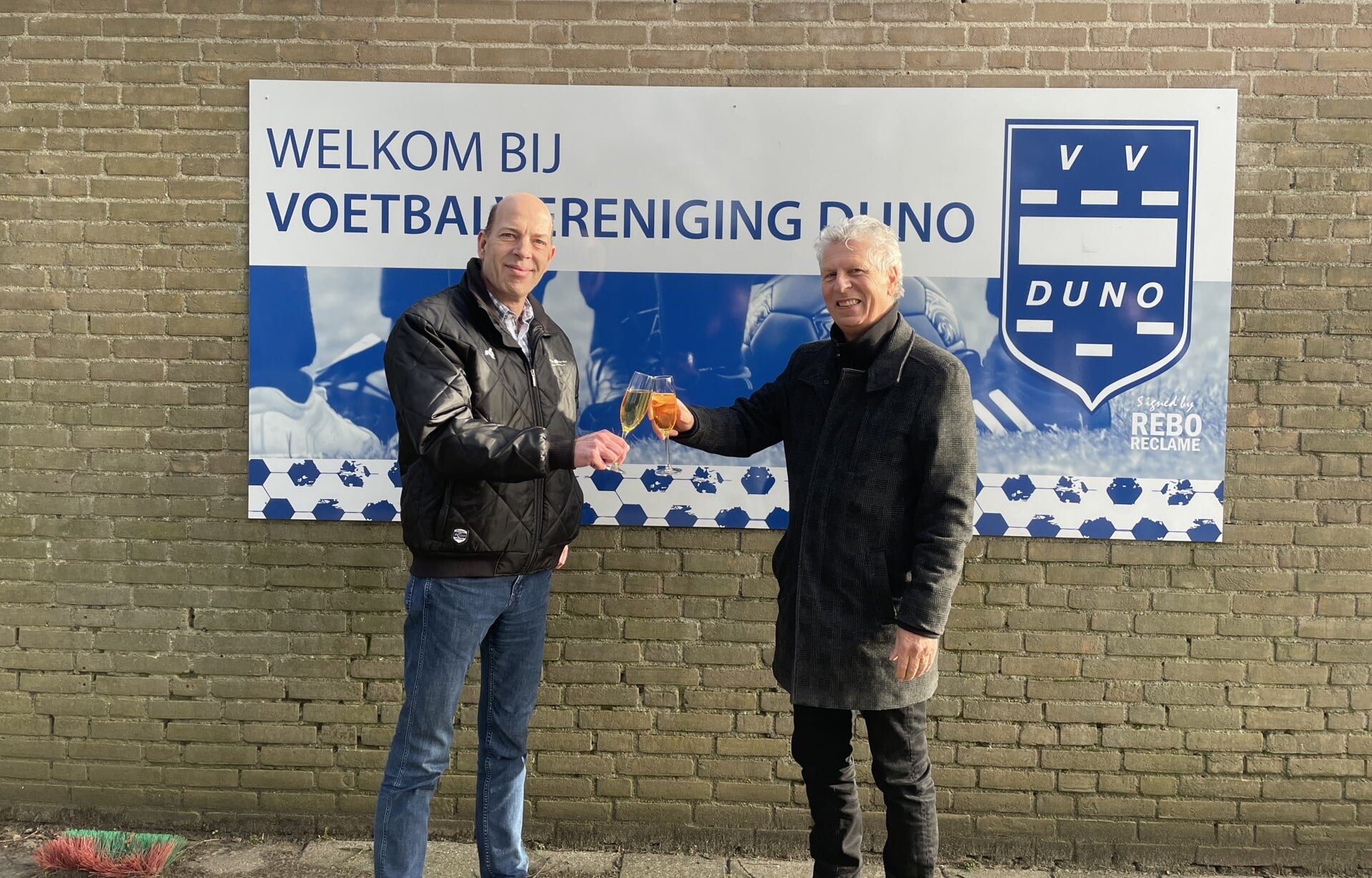 Harm Beumer, Manager Sport & Football bij Fletcher Football (links) en Duno-voorzitter Henk Puijen proosten op de ondertekening van de 3-jarige contractovereenkomst met de Gemeente Renkum over Sportpark De Waaijenberg.