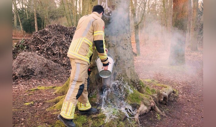 De brandweer probeerde eerst met een aantal emmers water de brand, die er vooral uitzag als een rokende boom, te blussen. 