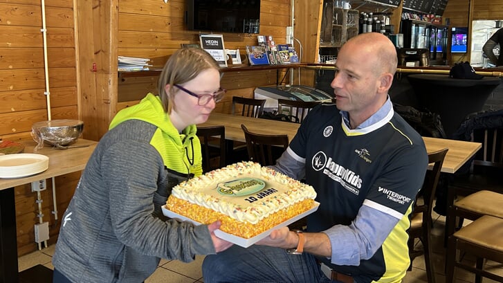 Voorzitter Bas van Eijndhoven overhandigt een van de G-hockeyers een heerlijk taart vanwege het jubileum.