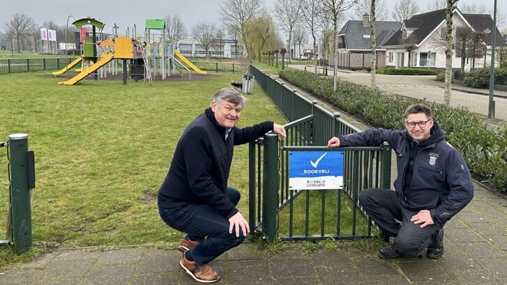 Wethouder Henk Vlastuin en speeltuinbeheerder Berry Schoolderman bij het Rookvrij-bord aan De Omloop.