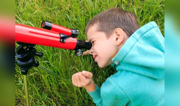 Kind kijkt dor  telescoop