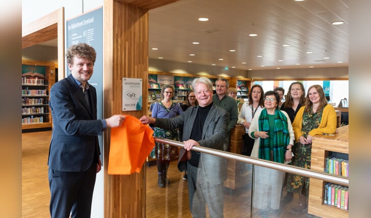 Wethouder Tyas Bijlholt (links) en directeur Erno de Groot onthullen de plaquette in het gebouw van de bibliotheek aan het Eemplein.