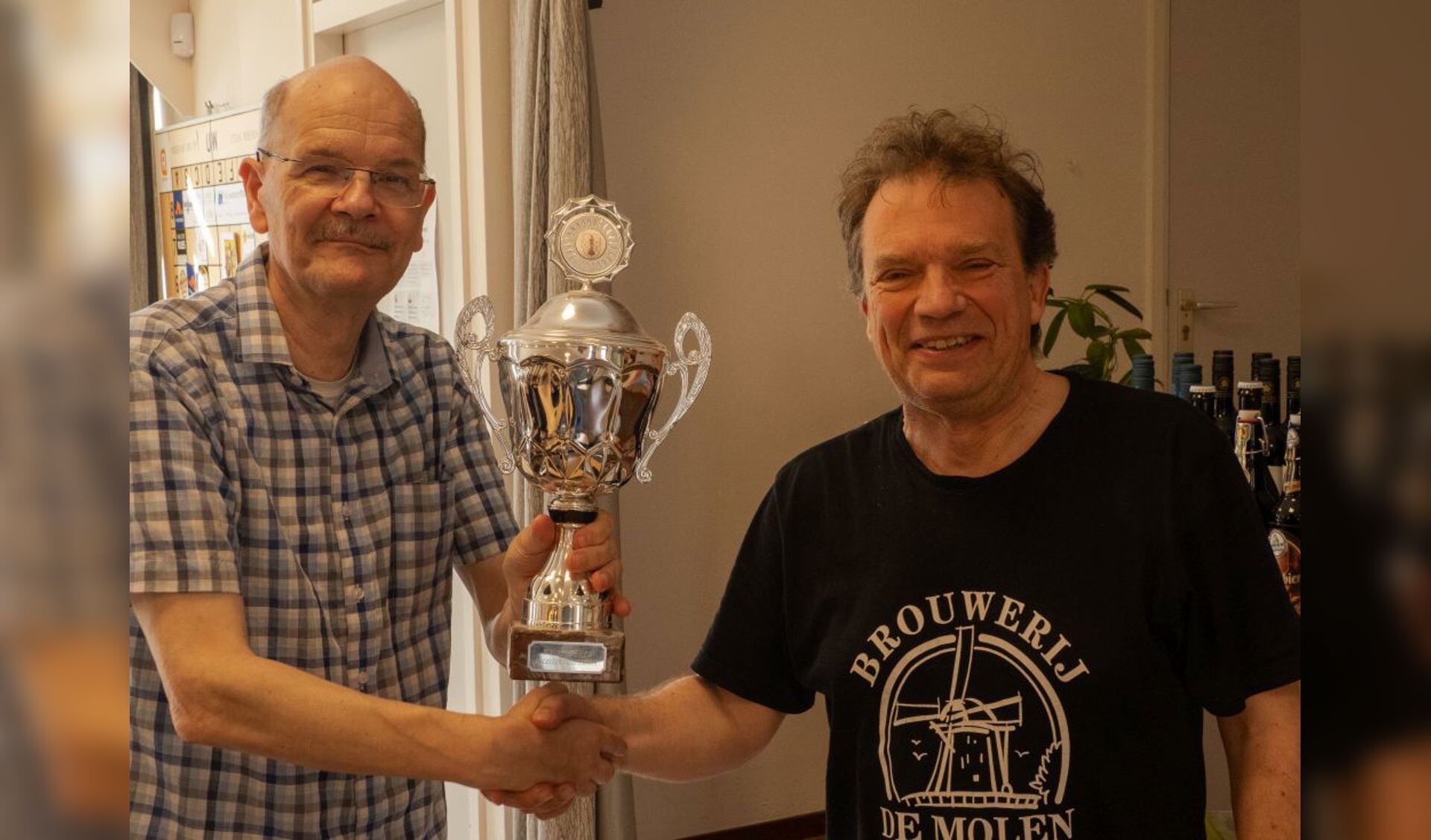 Toernooidirecteur Mark van Hulst overhandigt de wisselbeker aan de nieuwe kampioen Heico Kerkmeester