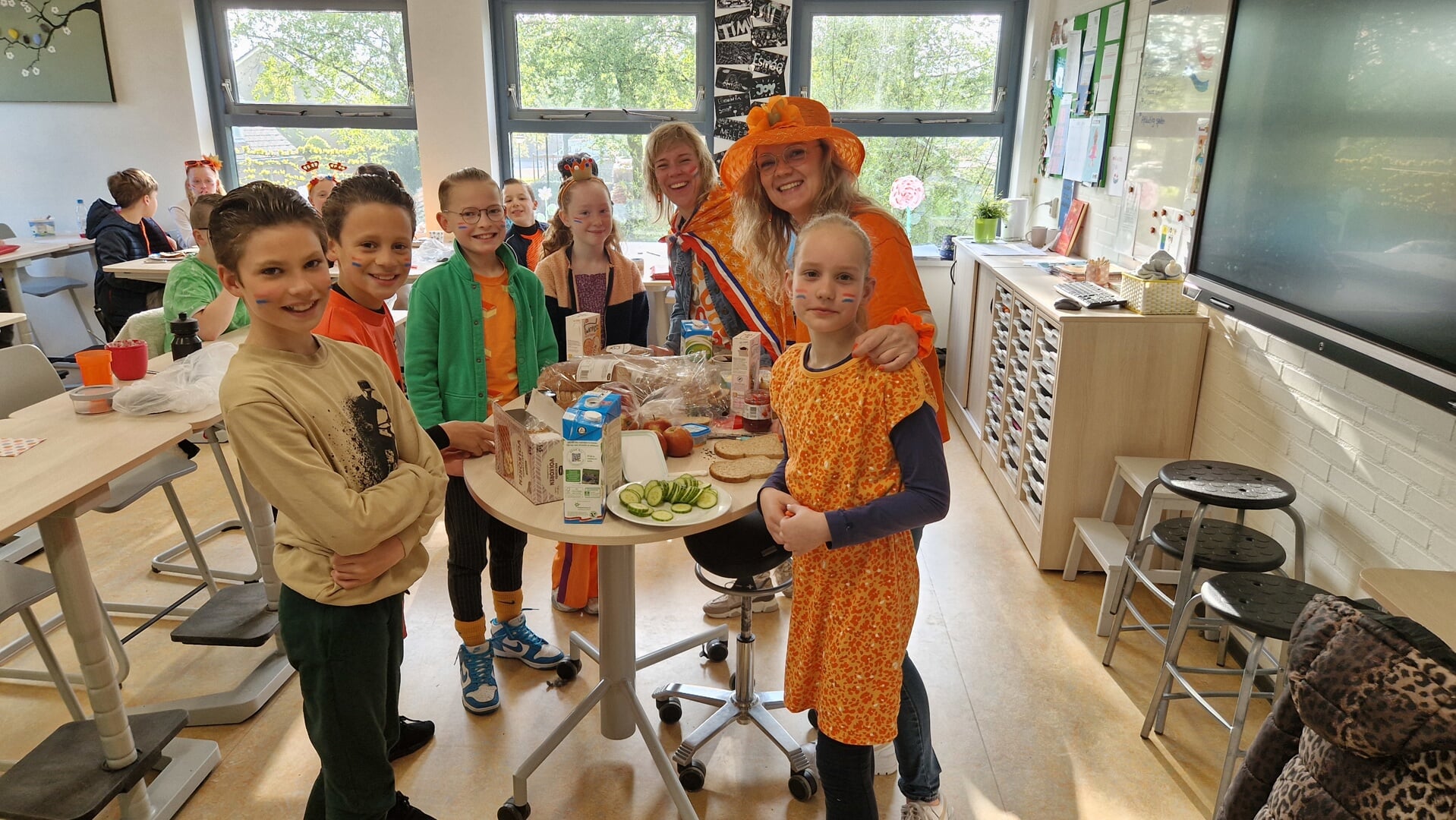 Juf Marit (met de hoed op) en moeder Sanne smeren de boterhammen voor groep zeven