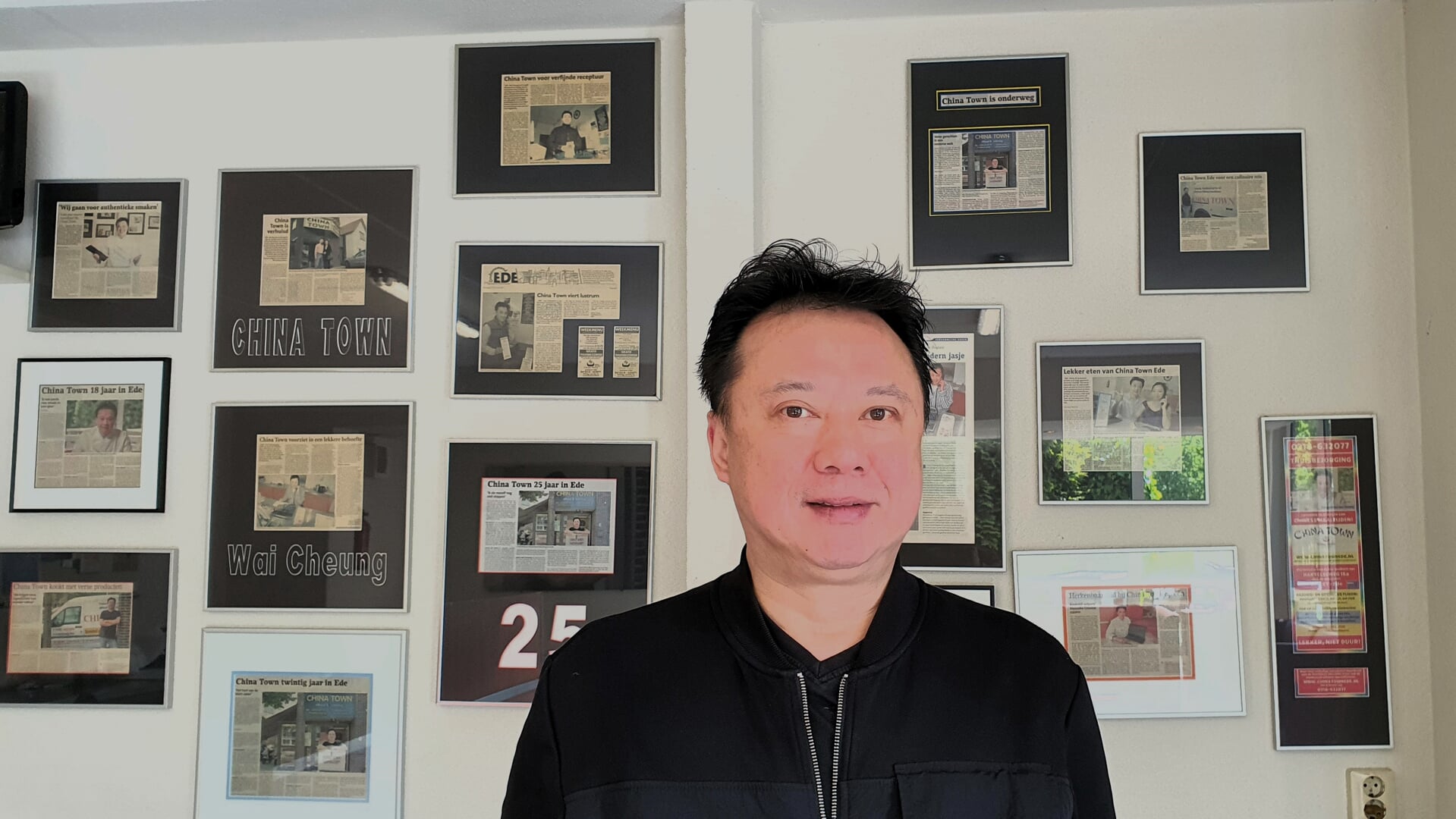 Wai Cheung voor de muur met artikelen over zijn zaak.