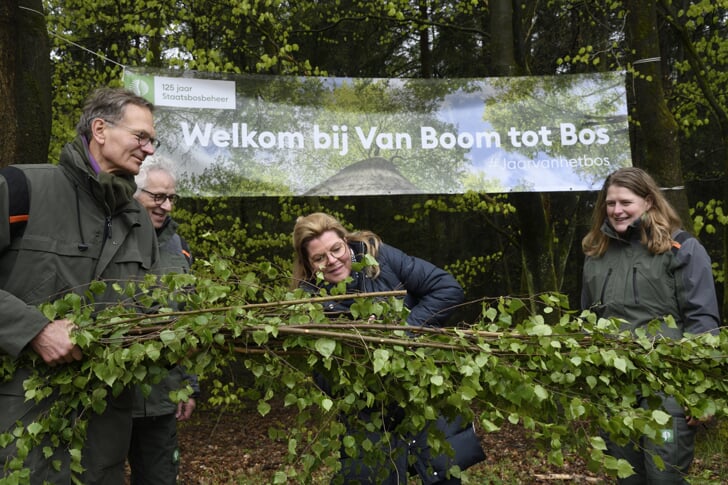 Met een stevige takkenschaar knipt minister Christianne van der Wal een lint gemaakt van berkentakken door. Daarmee opende ze in Garderen de allereerste 'Van Boom tot Bos' wandelroute. Directeur Sylvo Thijsen van Staatsbosbeheer (links) en boswachter Andy Liebrand en Jody Bennink (rechts) kijken toe.  